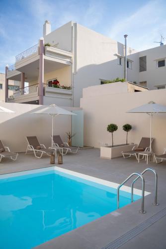 a pool with chairs and umbrellas next to a building at Selected Suites in Chania Town