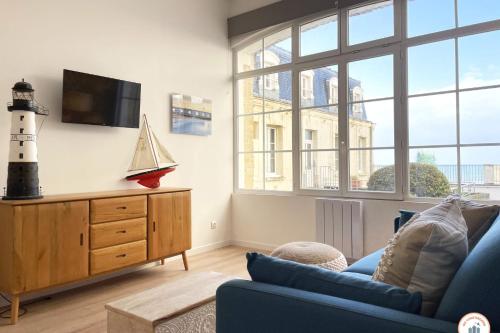 un salon avec un canapé bleu et une télévision dans l'établissement Le Sunset - Vue Mer - Accès plage privé, à Trouville-sur-Mer