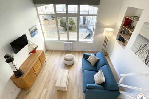 un salon avec un canapé bleu et une fenêtre dans l'établissement Le Sunset - Vue Mer - Accès plage privé, à Trouville-sur-Mer