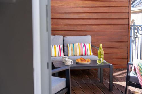 eine Couch auf einer Terrasse mit einem Tisch und einer Obstschale in der Unterkunft Maison de vacances avec Garage privé in Les Sables-dʼOlonne