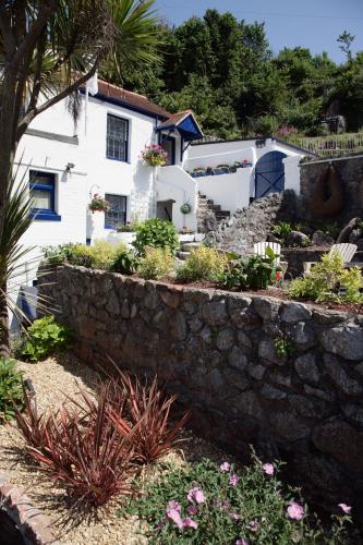 a white house with a stone wall and flowers at Cary Arms & Spa in Torquay