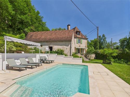 une piscine avec des chaises et une maison dans l'établissement Villa 'Le Roc' pour 11, jardin et piscine, à Thonac
