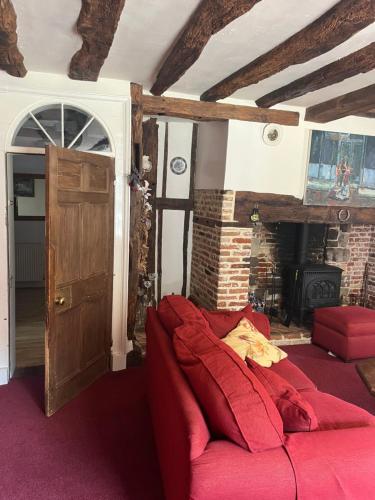 a living room with a red couch and a fireplace at Chilton Manor House in Murston