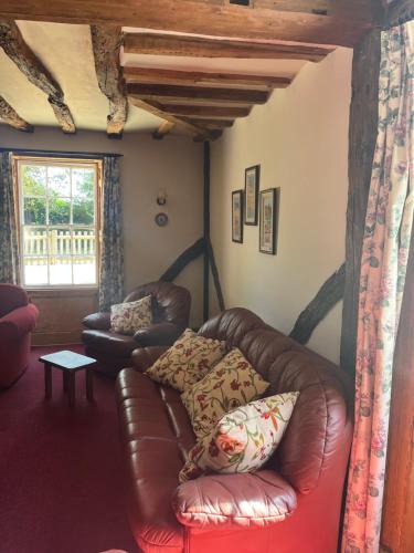 a living room with a leather couch and a window at Chilton Manor House in Murston