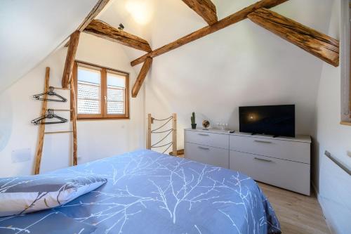 - une chambre avec un lit bleu et une télévision dans l'établissement Maisonnette Alsacienne en plein coeur de Turckheim, à Turckheim