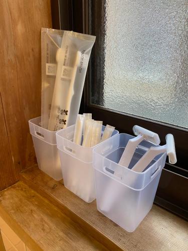 three plastic containers sitting on a window sill at Naoshima Haru House in Naoshima