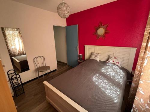 une chambre avec un grand lit avec un mur rouge dans l'établissement Appartement Beau Rivage Narbonne Plage, à Narbonne-Plage