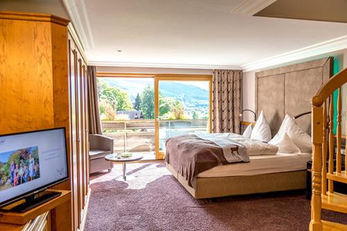 a bedroom with a bed and a large window at Hotel Heselbacher Hof in Baiersbronn
