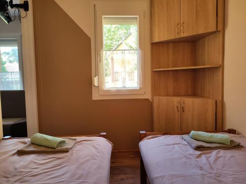 two beds in a room with a window at Estike Apartmanok in Tiszafüred