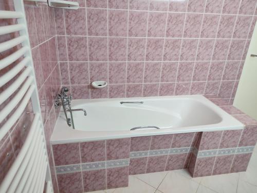 a bath tub in a bathroom with pink tiles at Estike Apartmanok in Tiszafüred
