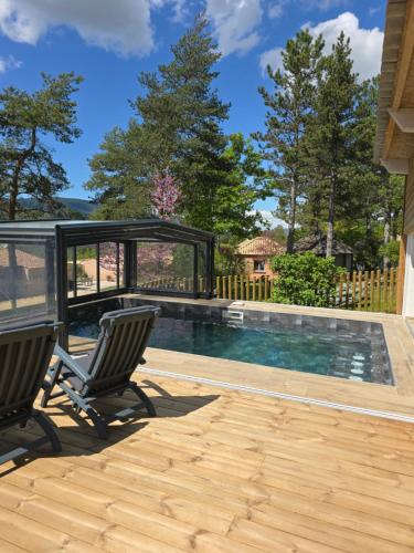a swimming pool with two chairs on a deck at Domaine du Val de Sault in Sault-de-Vaucluse