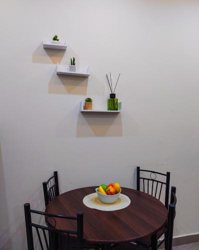 a wooden table with a bowl of fruit on it at Queens View Apartment in Accra