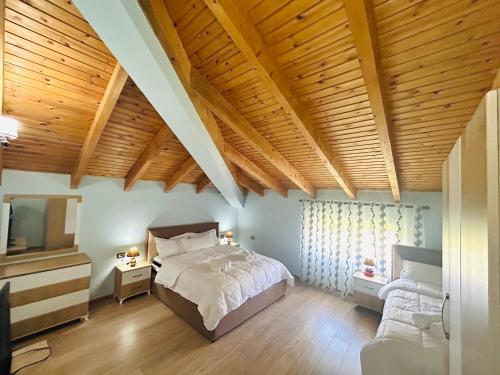 a bedroom with a bed and a tv and wooden ceilings at Bujtina Bashllari in Zvarisht