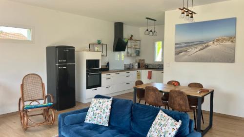 un salon avec un canapé bleu et une cuisine dans l'établissement Alice’s house, Maison & Grange à 10km de l’Océan, à Naujac-sur-Mer