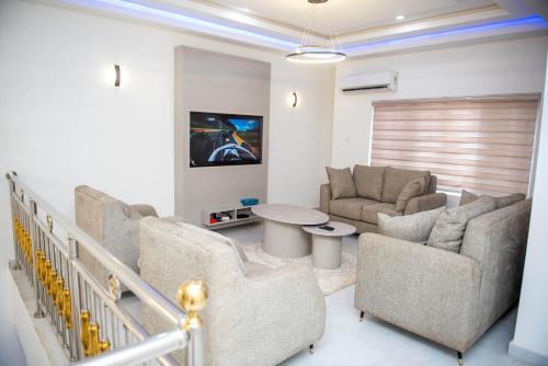 a living room with a couch and chairs and a tv at BCL Homes and Apartments in Rubuchi