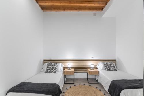 two beds in a room with two tables at La Lajita in Tafira Baja