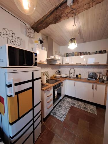 une cuisine avec des armoires blanches et un micro-ondes dans l'établissement Le Lodge Keraën, à Clermont-lʼHérault
