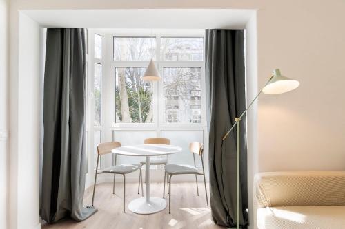 a table and chairs in a room with a window at Estoril One - New apartment in Estoril