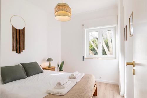 a white bedroom with a bed and a window at Estoril One - New apartment in Estoril