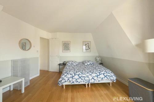 - une chambre mansardée avec un lit et un bureau dans l'établissement Lovely 2 bedrooms - Paris - rue de Prague - Flexliving, à Paris