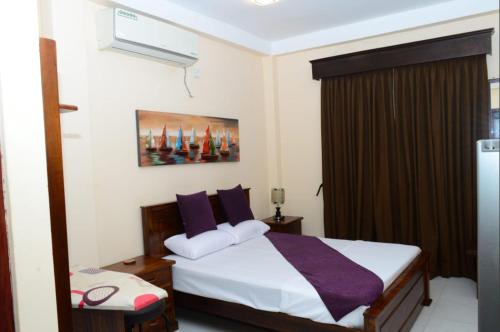 a bedroom with a bed with purple pillows at Abbi Holidays - Private Apartment Negombo in Negombo