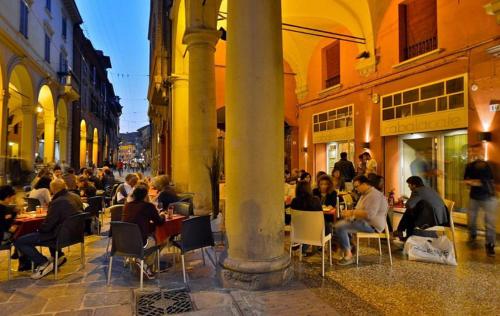 Un groupe de personnes assises à des tables dans une rue dans l'établissement Residenza Maggiore 10 - Affittacamere - Guest House, à Bologne