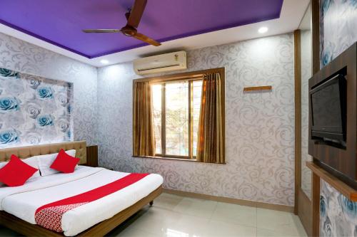 a bedroom with a bed with red pillows and a tv at Hotel O Yatri Yadgar in Mumbai