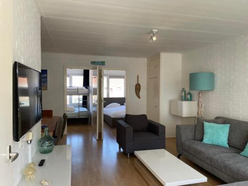 a living room with a couch and a tv at Heerlijke vakantiehuizen in Egmond in Egmond aan Zee