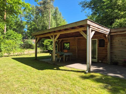 a wooden pavilion with a table in a yard at Boshuisje in Nutter