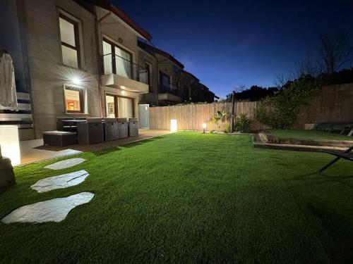 a yard with a green lawn in front of a house at Adosado O Recuncho de Arra in Vista Alegre