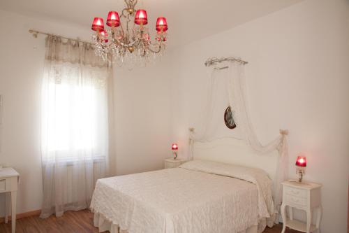 a white bedroom with a white bed with a chandelier at A Casa della Nonna in Cefalù