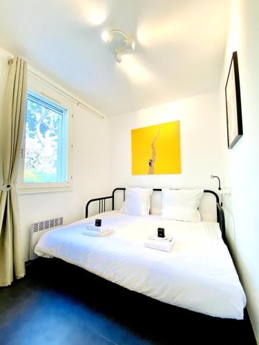 - une chambre avec un lit blanc et 2 plateaux dans l'établissement Pinède, calanques & jeux en famille pour 1 à 5 personnes, à Cassis