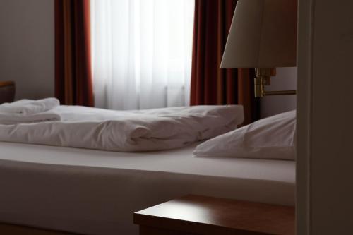 a bed with white sheets sitting next to a window at Hotel an der Therme in Bad Dürkheim