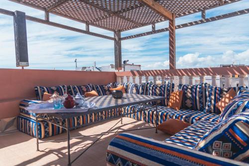 a patio with couches and a table on a roof at Roudania Tamraght Ocean View - Private Rooms And Hostel Vibes in Tamraght Ouzdar