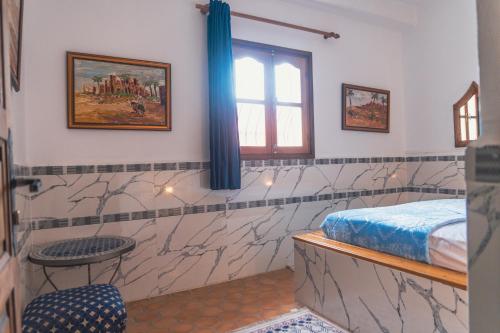 a room with a bed and a table and a window at Roudania Tamraght Ocean View - Private Rooms And Hostel Vibes in Tamraght Ouzdar