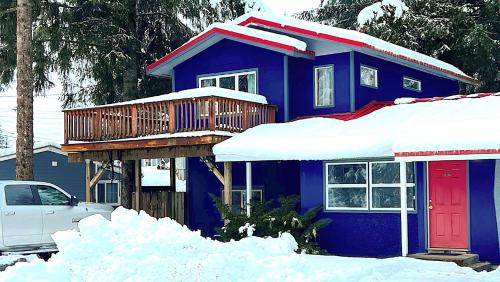 a blue house with a deck in the snow at Raw Gold - Affordable, Near Mendenhall Glacier, Trails, and Conveniences - DISCOUNTS ON TOURS! in Mendenhaven