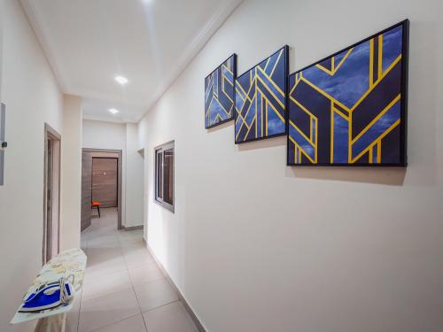 a hallway with blue and yellow paintings on the wall at Queens View Apartment in Accra