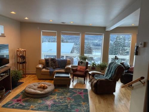 a living room with couches and chairs and windows at Home on the Hill at Kelli Creek in Juneau