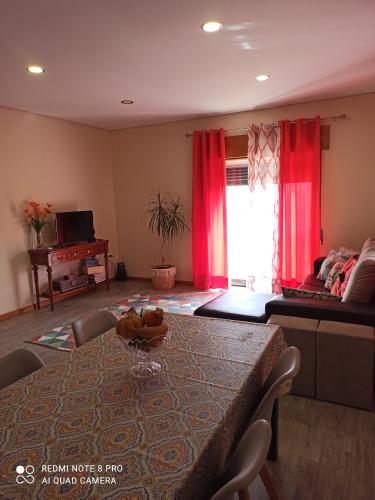 a living room with a table and red curtains at Casa Da Fonte Da Torre in Peso da Régua