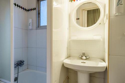 Un baño blanco con lavabo y espejo. en Hostal Austria, en Granada