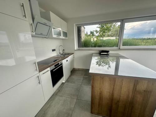 a kitchen with white cabinets and a sink and a window at Villa Rosemary Trieste HerMes arT in Sežana