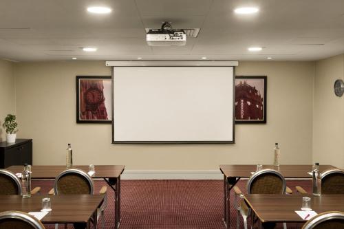 a conference room with tables and a projection screen at Crowne Plaza London Ealing by IHG in London