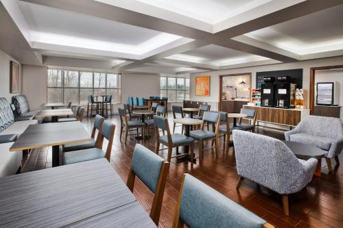 a restaurant with tables and chairs and windows at Holiday Inn Express Hotel & Suites Auburn Hills by IHG in Auburn Hills
