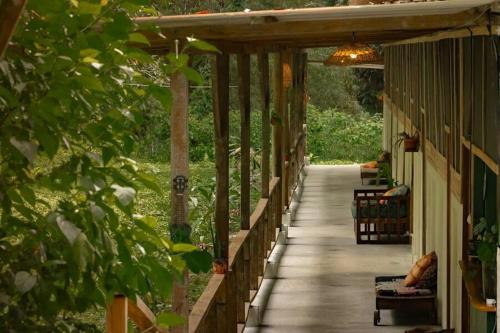 a porch of a house with a person sitting on a bench at Smile Jungle Hostel in Puerto Viejo