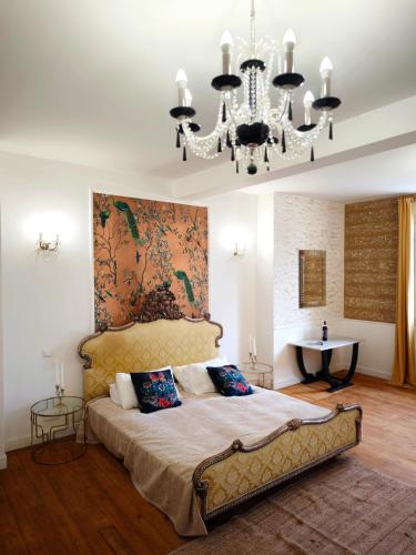 - une chambre avec un grand lit et un lustre dans l'établissement Chateau La Croix De Millorit, à La Reuille