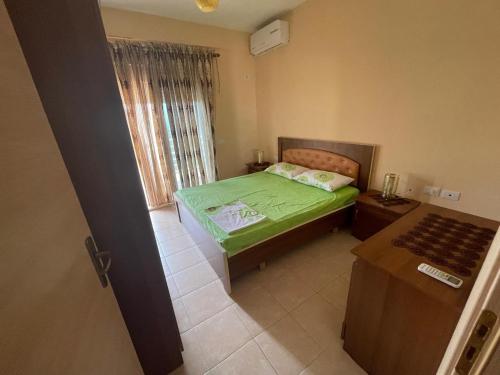 una piccola camera da letto con un letto verde e una finestra di Seaside Apartment Vlora a Vlorë