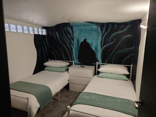 two beds in a room with a painting on the wall at Malthouse Farm Cottage Batcave in Stoke on Trent