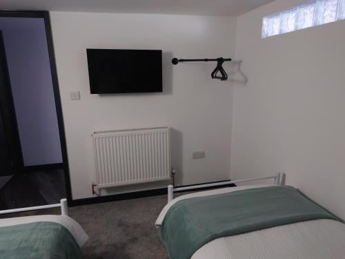 a room with two beds and a television on the wall at Malthouse Farm Cottage Batcave in Stoke on Trent