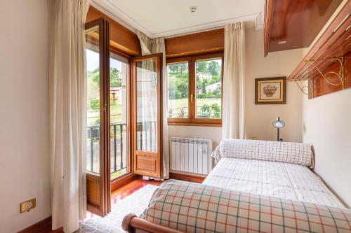 a bedroom with a bed and two windows at Luminoso apartamento en Liérganes in Liérganes