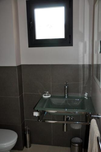 La salle de bains est pourvue d'un lavabo vert et d'une fenêtre. dans l'établissement Family suite with private terrace, à Nice